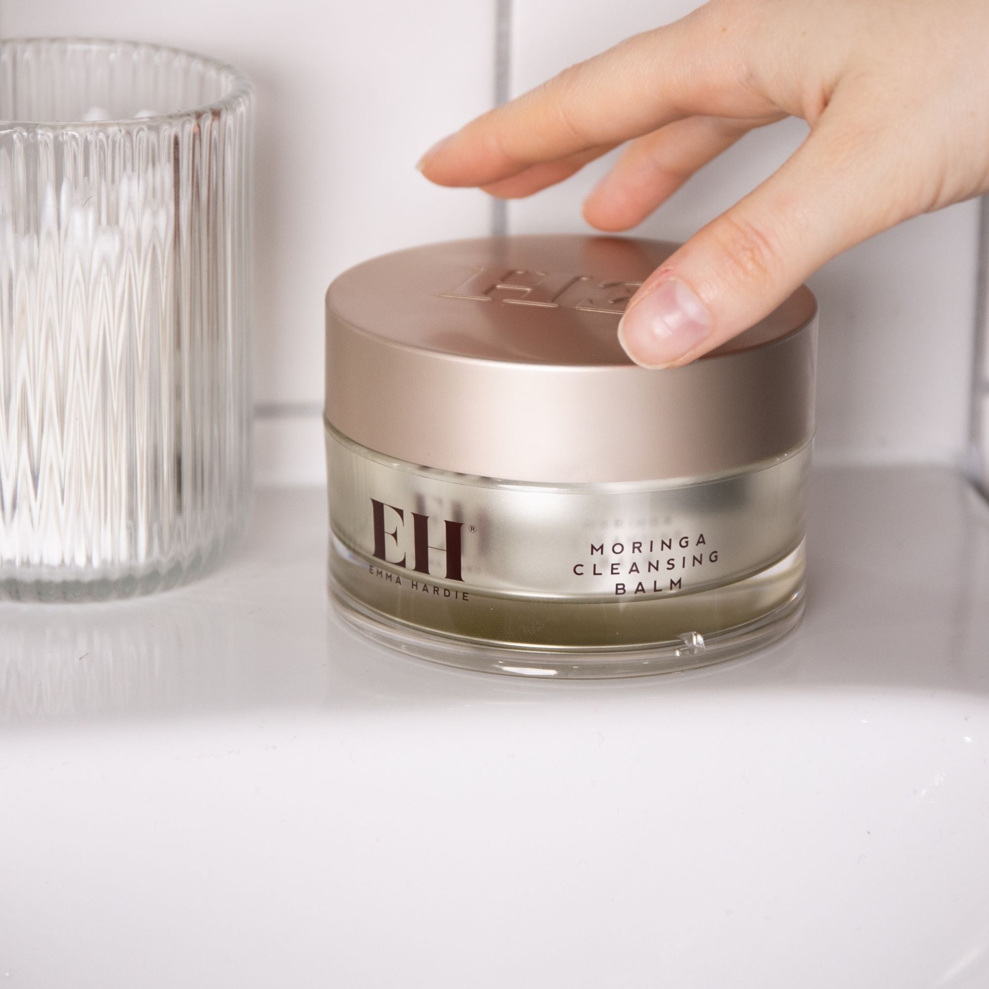 Hand opening a jar of Emma Hardie Moringa Cleansing Balm.