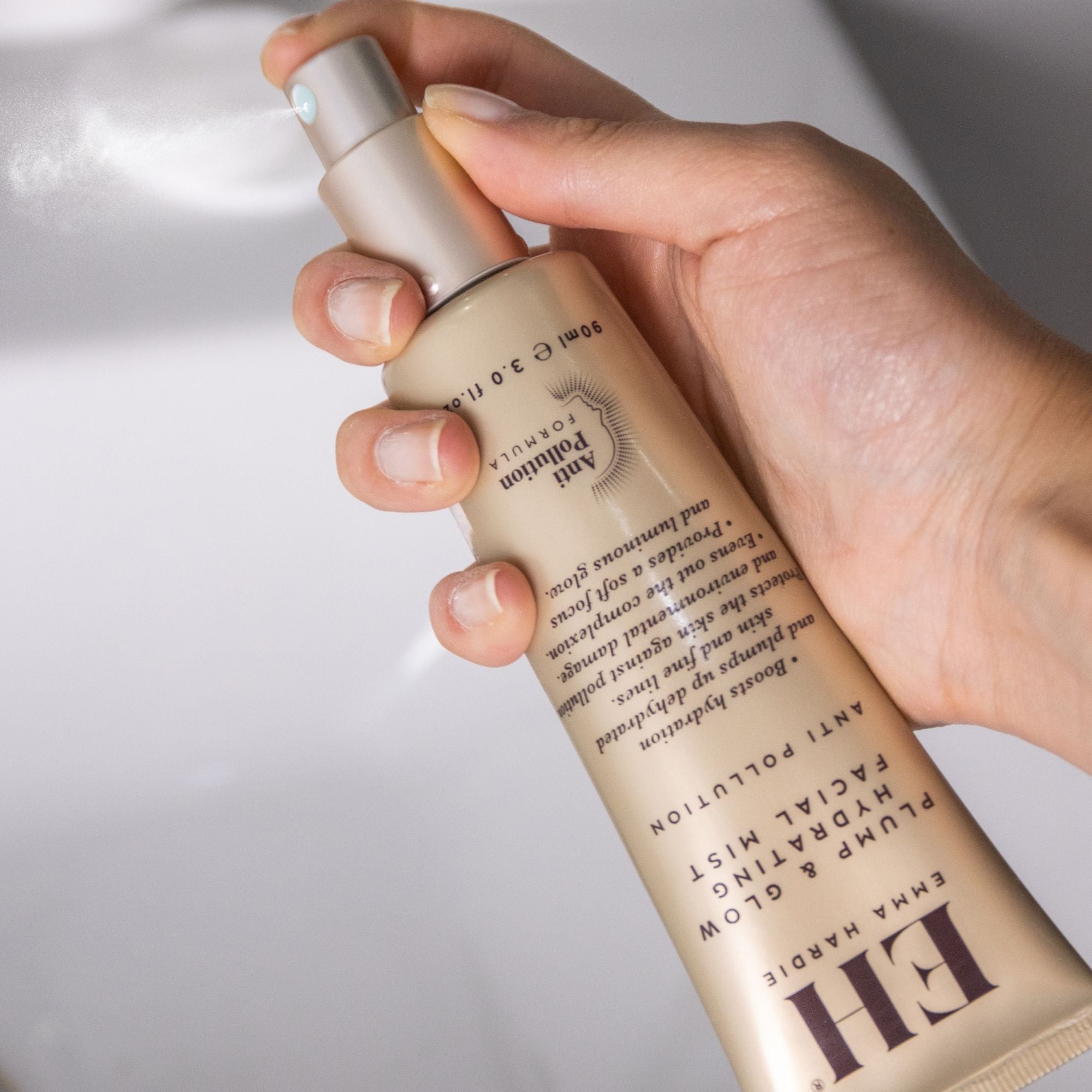 Hand holding Emma Hardie Plump & Glow Hydrating Facial Mist and pressing the spray pump.