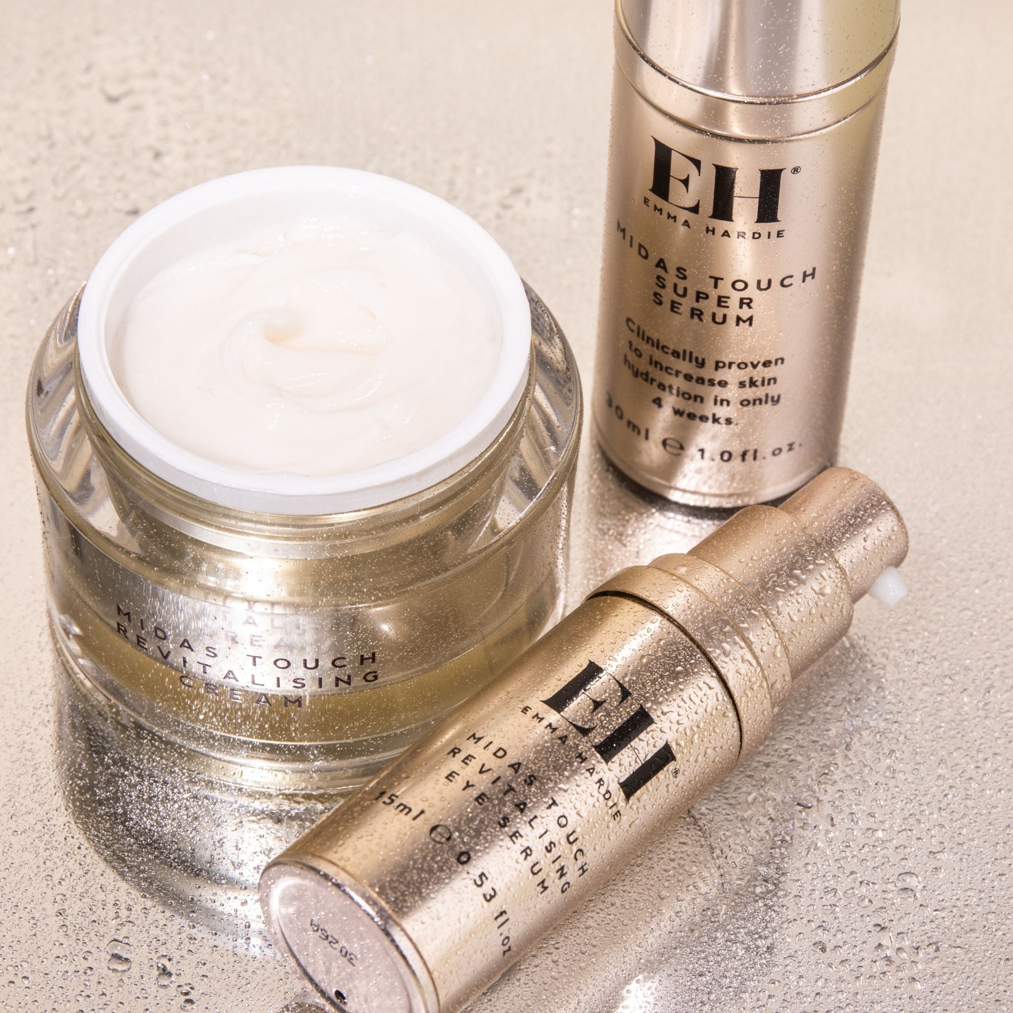 Midas Touch Revitalising Cream, Super Serum and Eye Serum arranged together on a textured neutral surface.