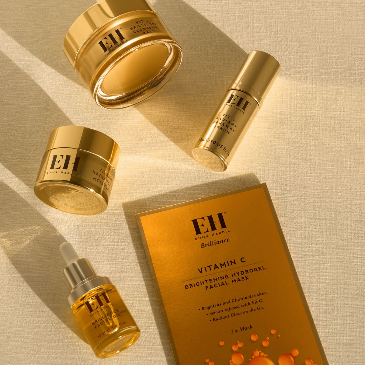 Emma Hardie Vit C Brilliance skincare collection arranged in warm sunlight, including balm, serum, moisturiser, facial oil and mask.