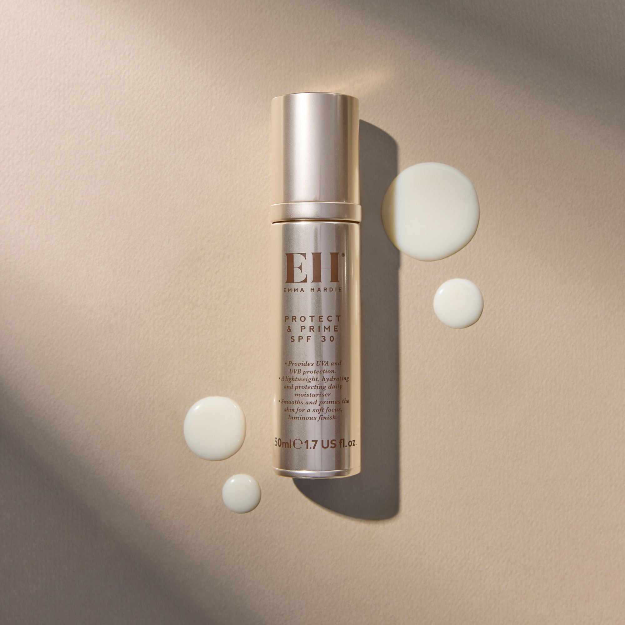 Emma Hardie Protect & Prime SPF30 bottle on a neutral background, surrounded by soft cream texture droplets.
