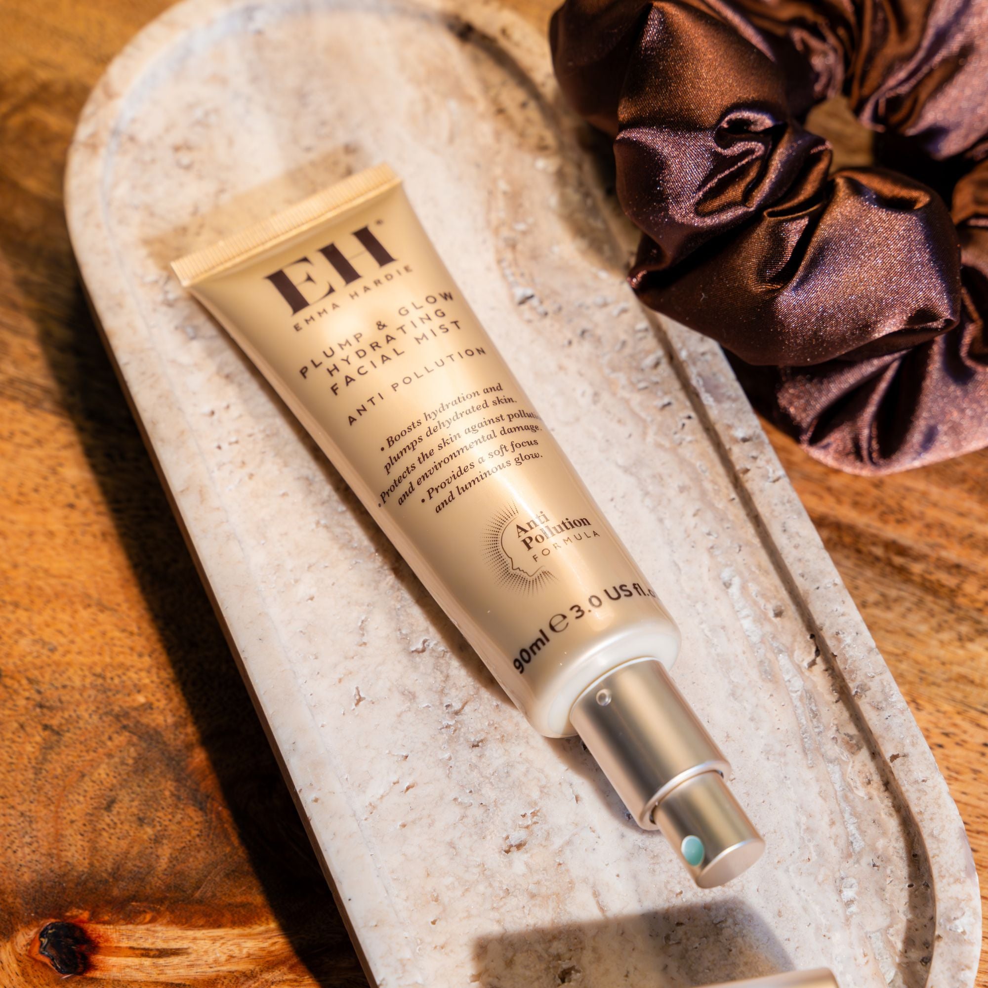 Emma Hardie Plump & Glow Hydrating Facial Mist on a stone tray, styled with a satin scrunchie and warm golden light.