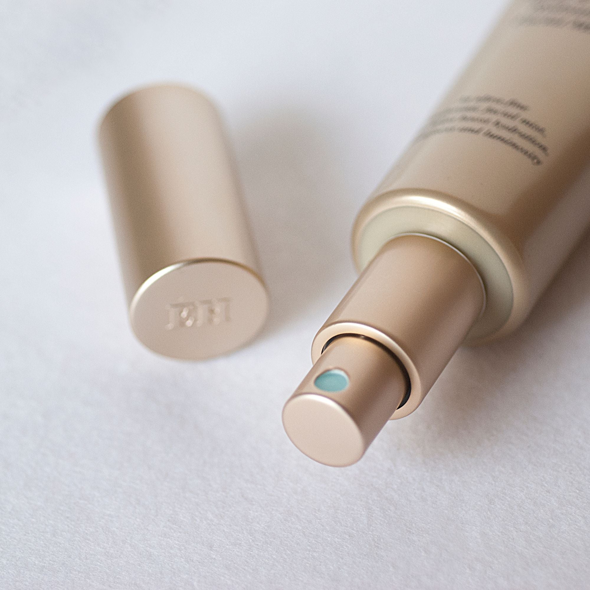 Close-up of the Emma Hardie Plump & Glow Hydrating Facial Mist spray bottle with the cap beside it on a soft white surface.