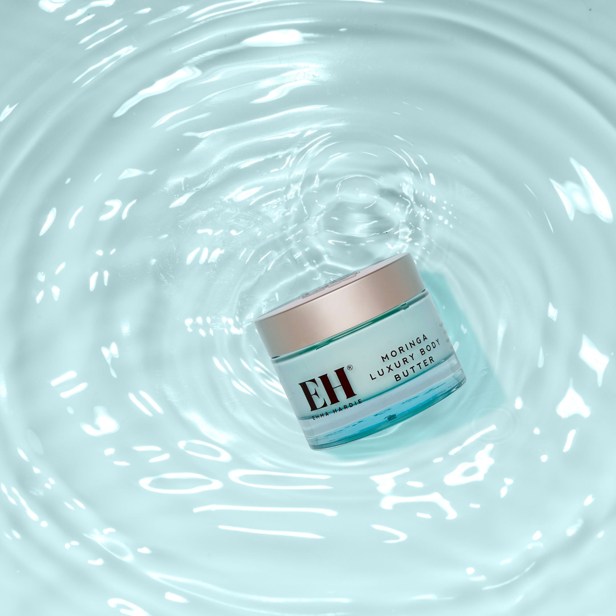 Jar of Emma Hardie Moringa Luxuy Body Butter floating on water with ripples.