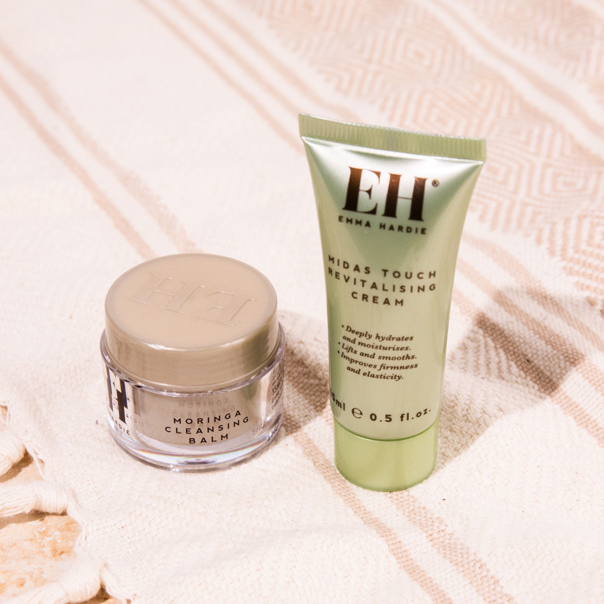 Travel sized Emma Hardie Moringa Cleansing Balm and Midas Touch Revitalising Cream displayed on a soft patterned towel.