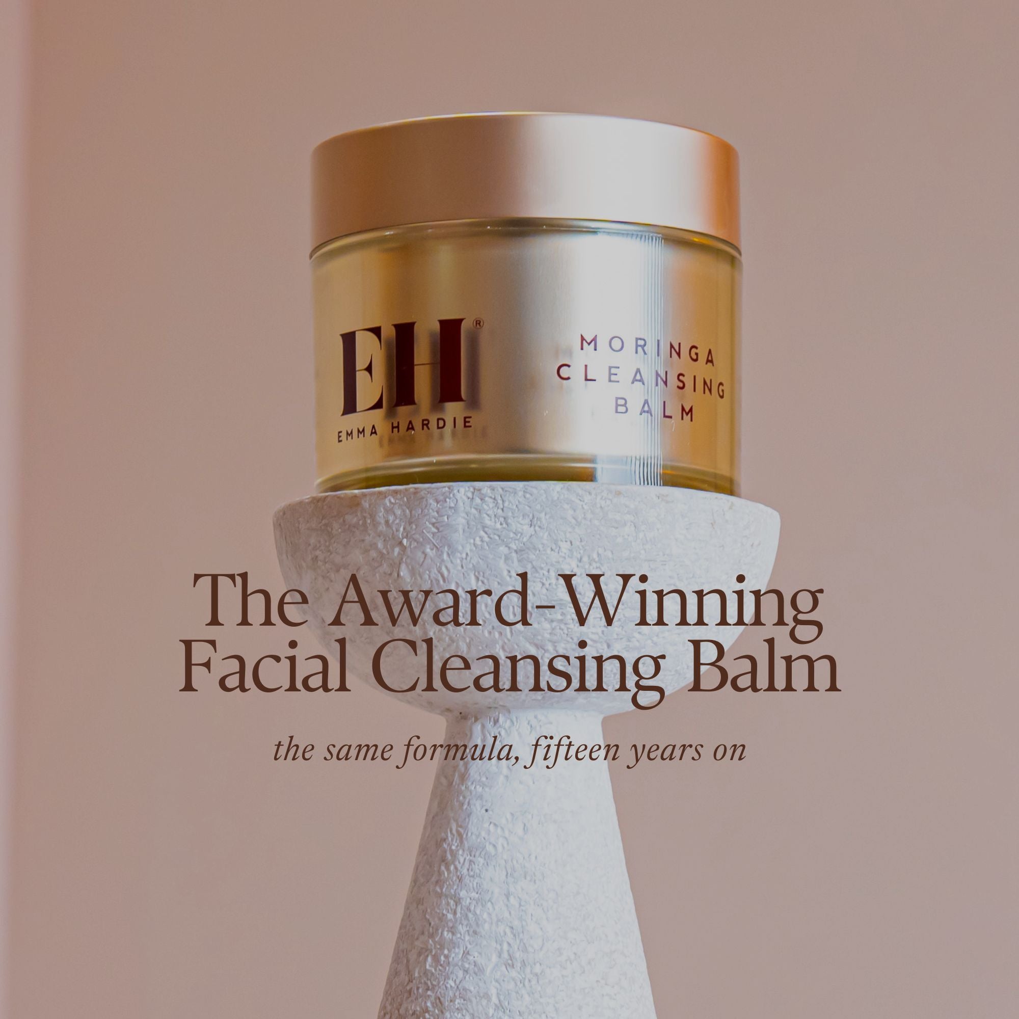 Emma Hardie Moringa Cleansing Balm on a textured stand with a beige background with the overlay text: 'The Award-Winning Facial Cleansing Balm. The same Forumula, fifteen years on'