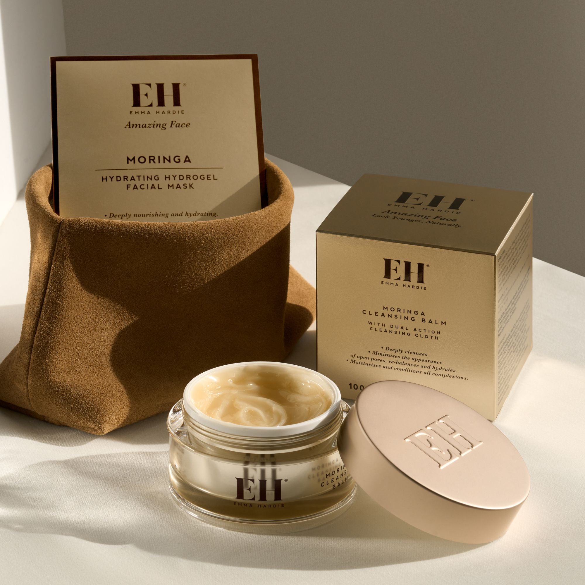 Emma Hardie Moringa Cleansing Balm displayed with its box and Moringa Hydrating Hydrogel Facial Mask in soft natural light.