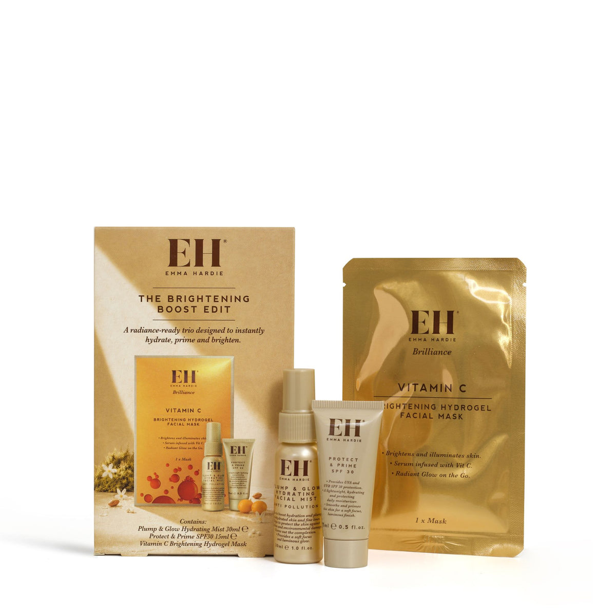 Emma Hardie Brightening Boost Edit gift set with facial mist, SPF primer and Vitamin C hydrogel mask beside its box on a white background.