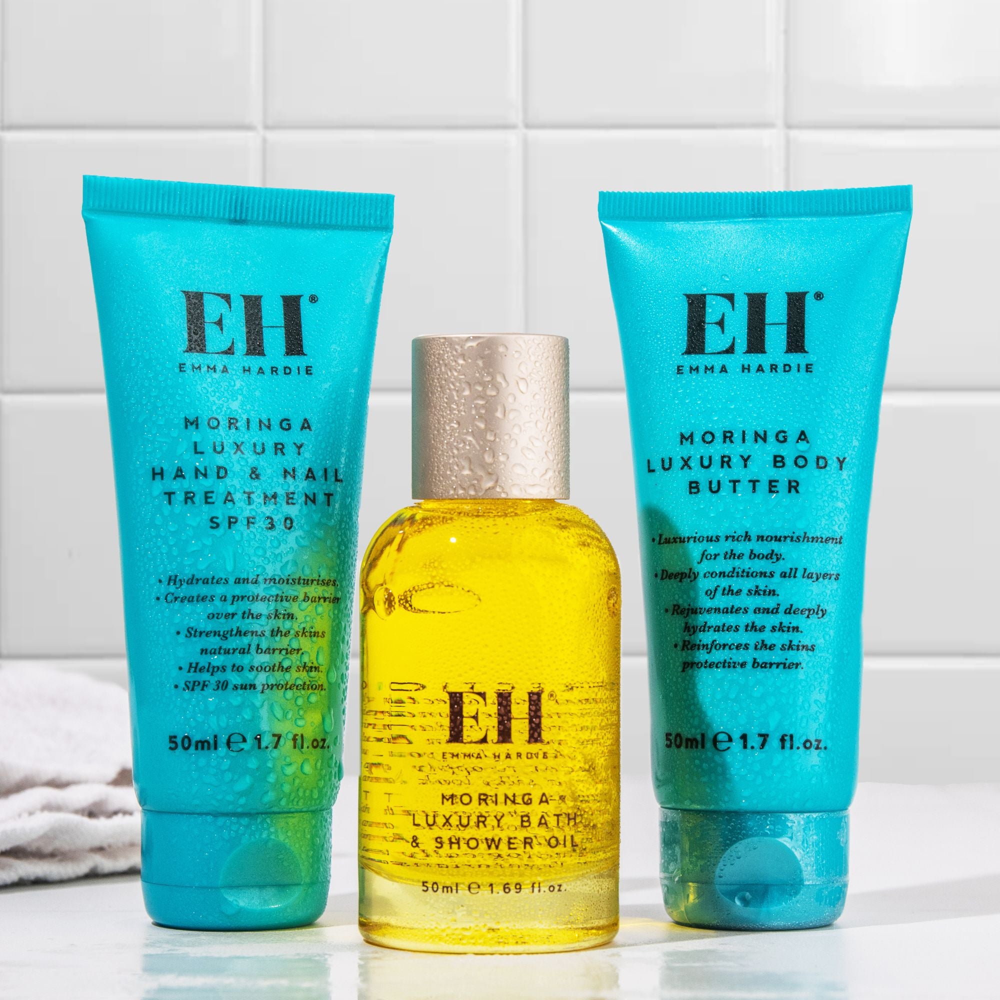 Emma Hardie Moringa body care collection with Luxury Body Butter, Luxury Hand and Nail Treatment SPF30 and Luxury Bath & Shower Oil on a bathroom counter.