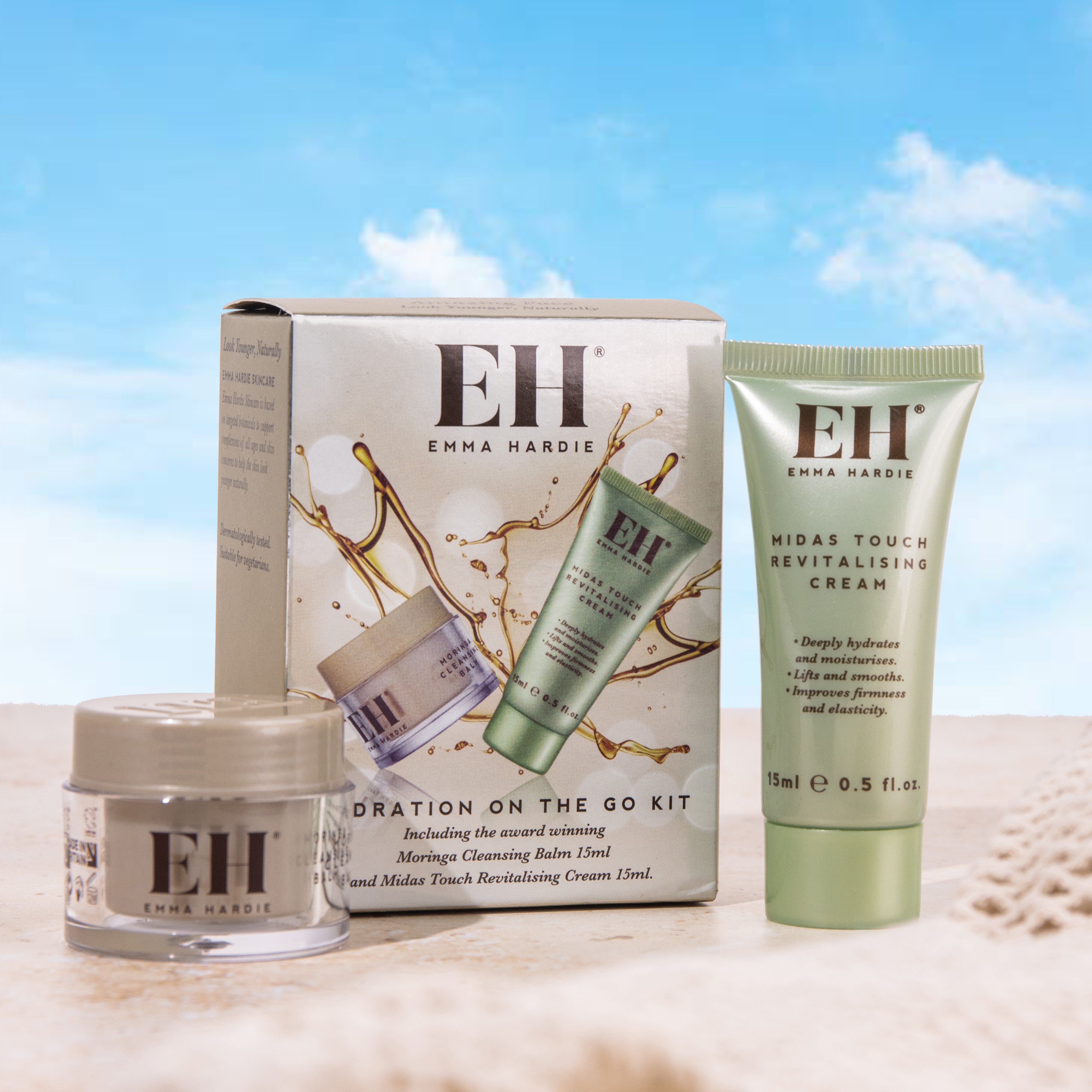 Emma Hardie Hydration On The Go Kit with Moringa Cleansing Balm and Midas Touch Revitalising Cream, styled against a soft blue sky background.