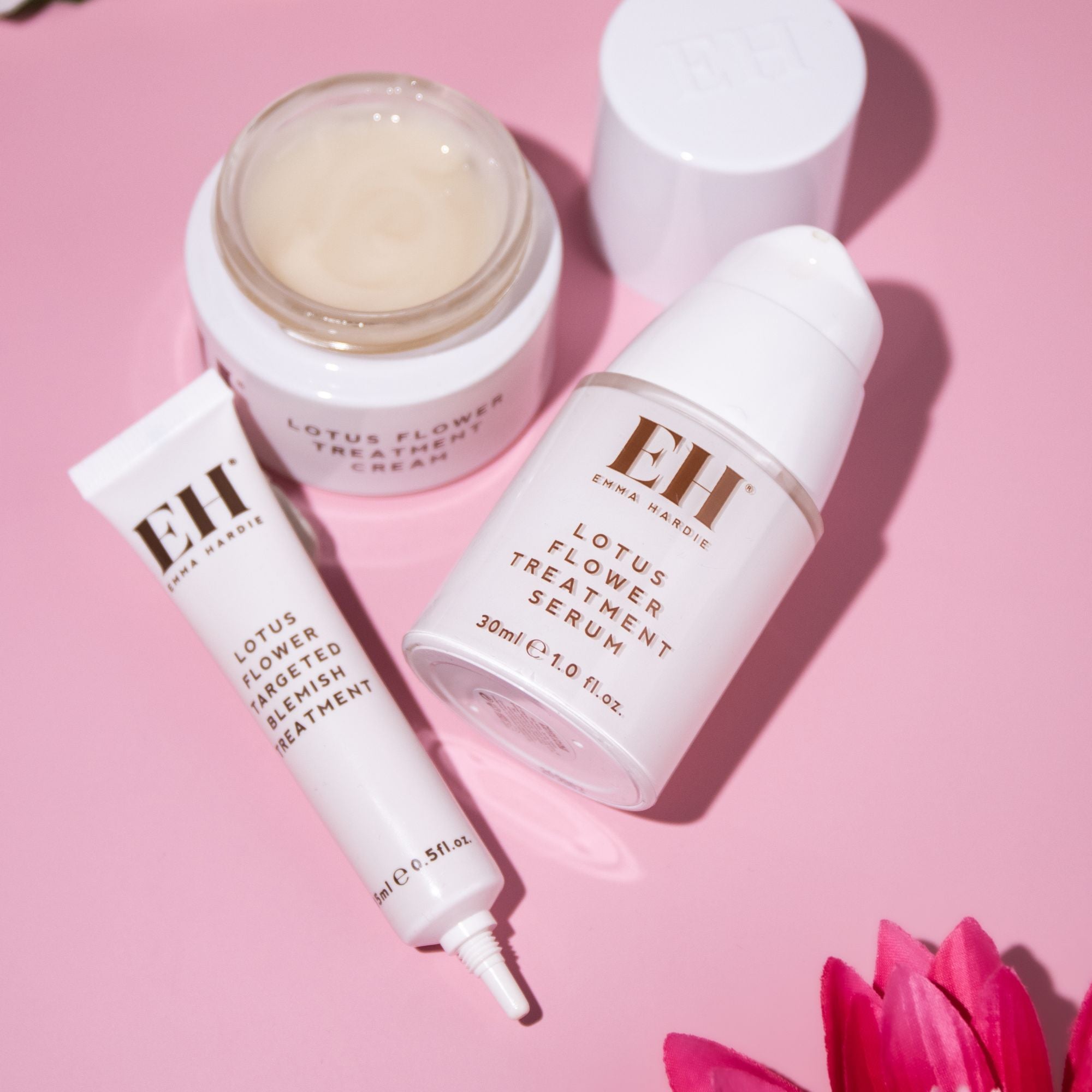 Emma Hardie Lotus Flower skincare range with Treatment Serum, Treatment Cream and Targeted Blemish Treatment on a soft pink background.