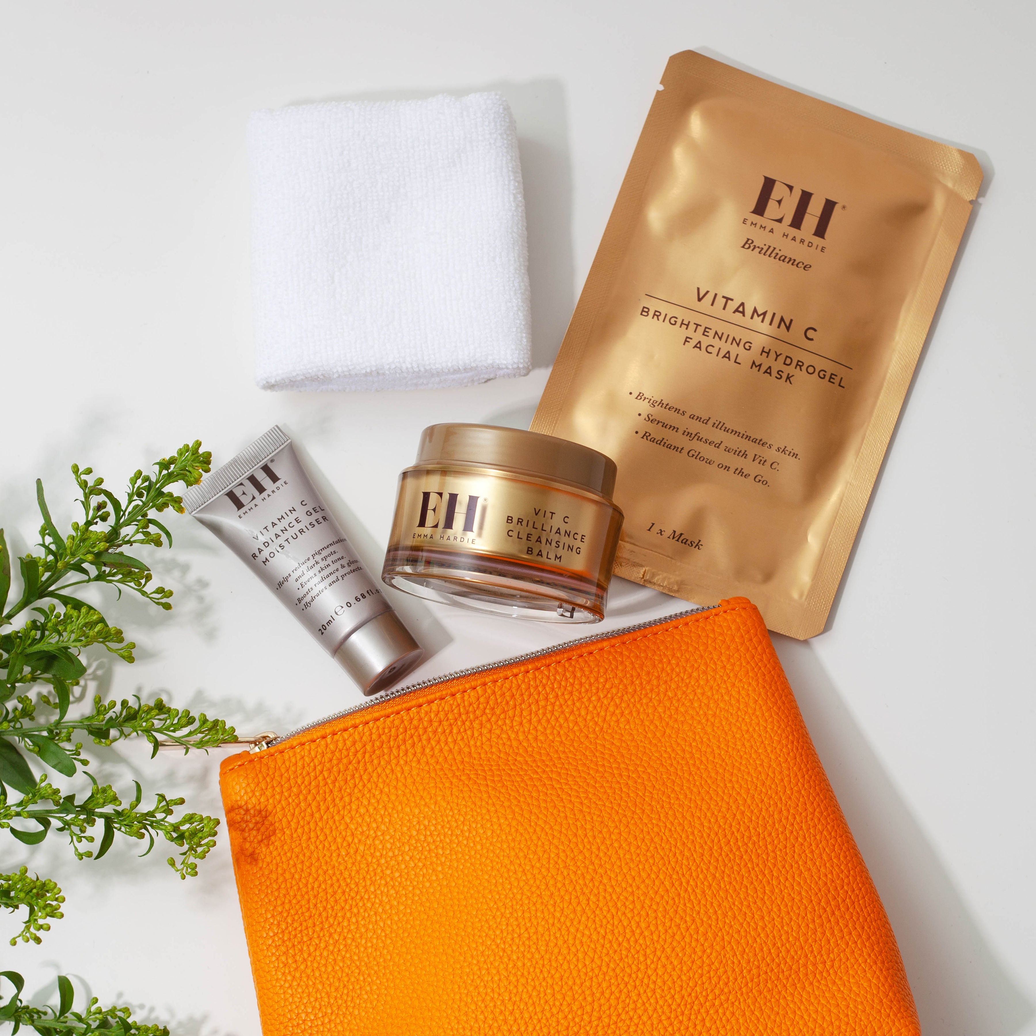 Emma Hardie Brilliance Edit with Vitamin C Brightening Hydrogel Facial Mask, Vit C Brilliance Cleansing Balm, mini skincare tube, cleansing cloth and orange wash bag.