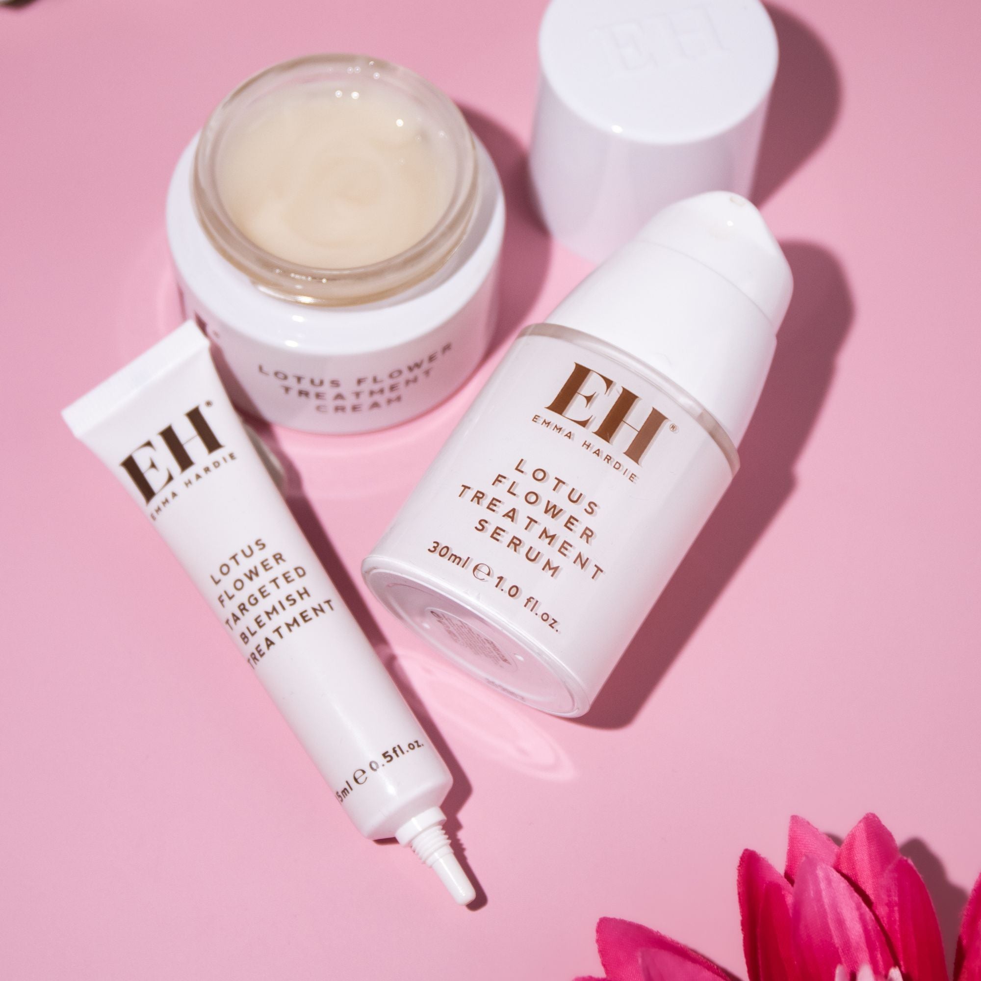 Emma Hardie Lotus Flower skincare range with Treatment Serum, Treatment Cream and Targeted Blemish Treatment on a soft pink background.