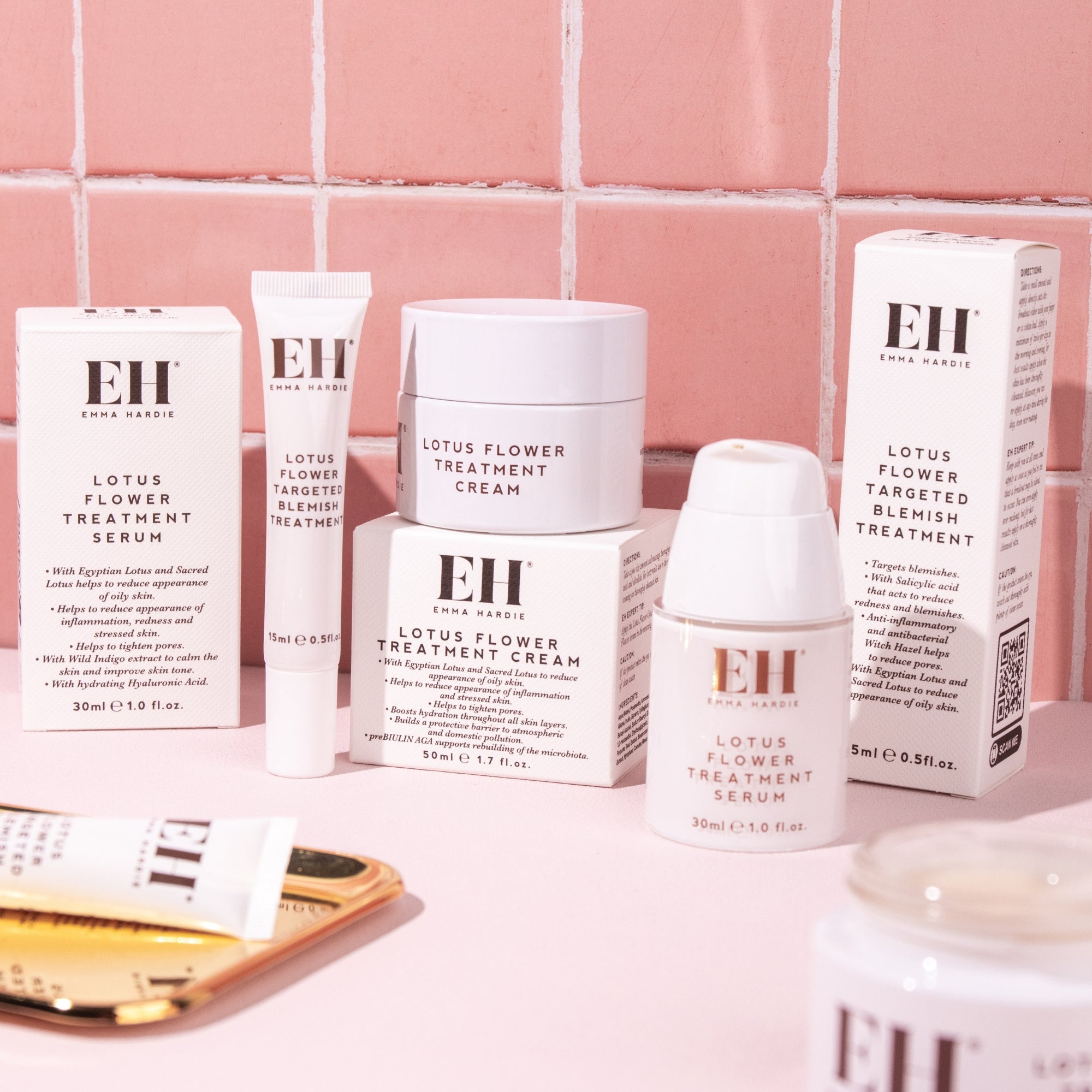 Emma Hardie Lotus Flower range, including Treatment Serum, Treatment Cream and Targeted Blemish Treatment, displayed against pink tiles.