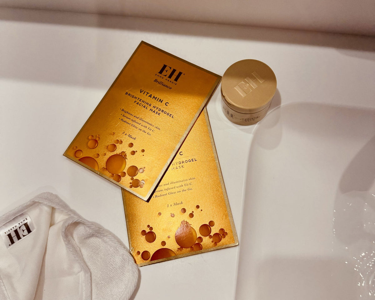 Vitamin C Brightening Hydrogel Facial Masks with a mini Emma Hardie skincare pot arranged on a cream surface in warm light.