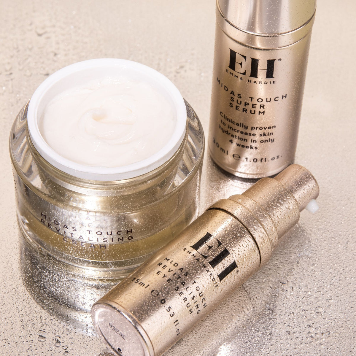 Midas Touch Revitalising Cream, Super Serum and Eye Serum arranged together on a textured neutral surface.