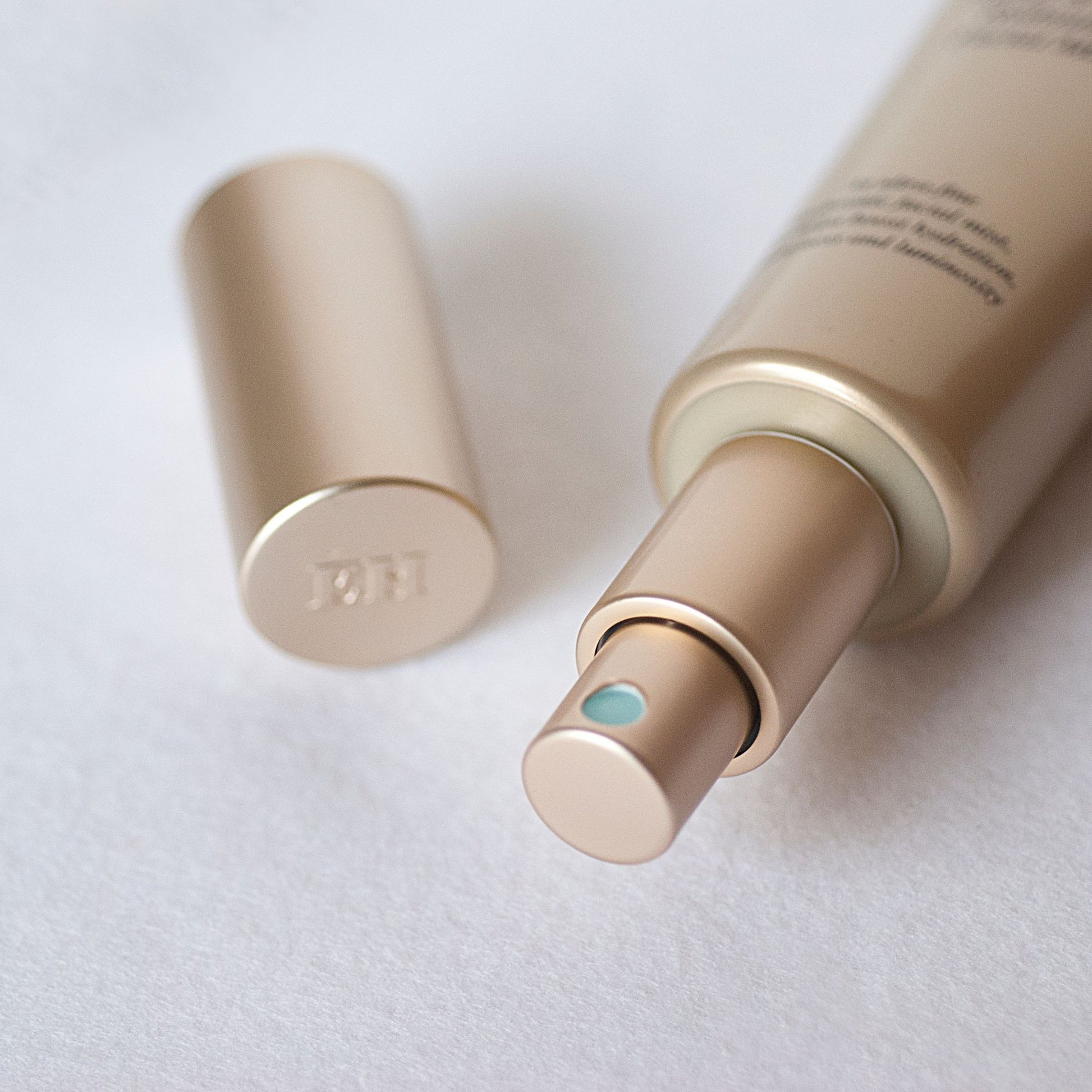 Close-up of the Emma Hardie Plump & Glow Hydrating Facial Mist spray bottle with the cap beside it on a soft white surface.