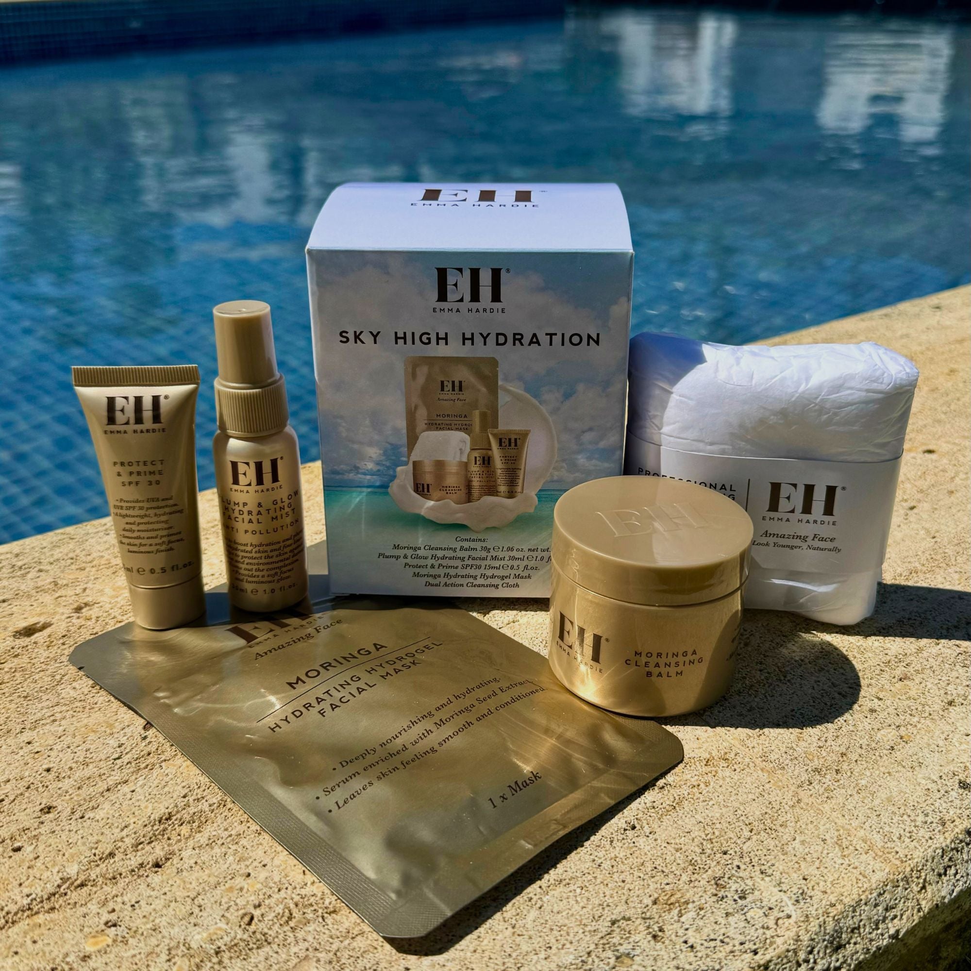 Emma Hardie Sky High Hydration travel skincare set displayed beside a swimming pool.